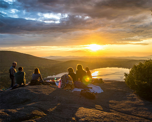 A large family looking at a sunset from a mountain.