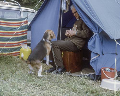 Older man and his dog in a tent.