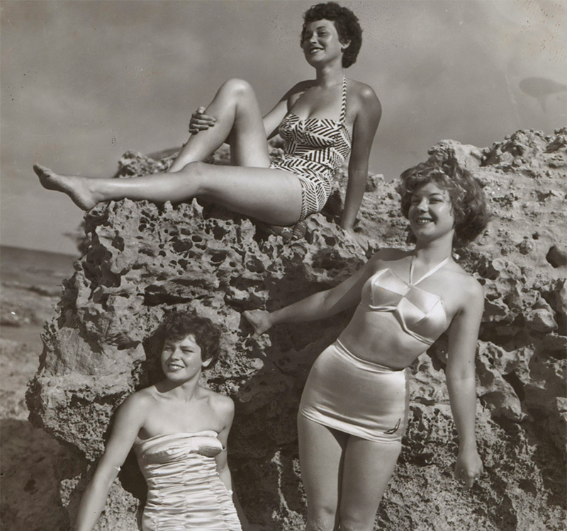 Black and white photo of three-woman sunbathing on a bolder.